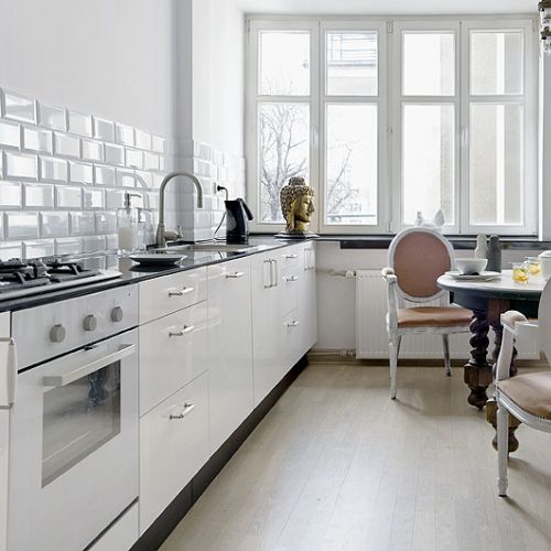 Proste szafki z białymi frontami w towarzystwkie antycznego stołu i krzeseł.