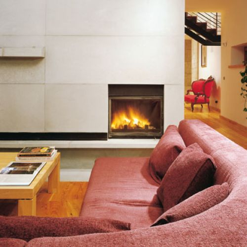 Przed minimalistycznym kominkiem mozna się rozsiąść w na wygodnej kanapie.