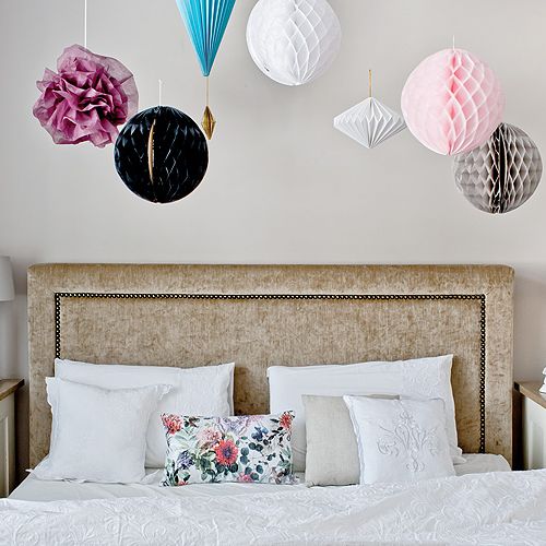 Ściany w perłowym różu i papierowe ozdoby pod sufitem.