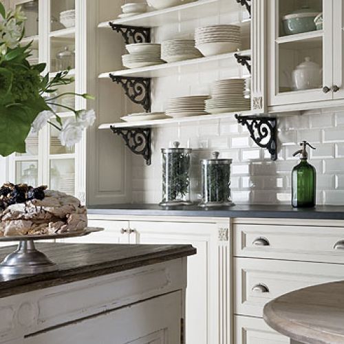 Stylizowana, biała kuchnia. Półki z dekoracyjnymi, żeliwnymi wspornikami. FABRYKA WNĘTRZ