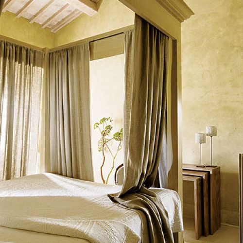 Surowe, drewniane stoły i składane krzesła inspirowane angielskimi meblami kolonialnymi solidne łoża z baldachimem obok