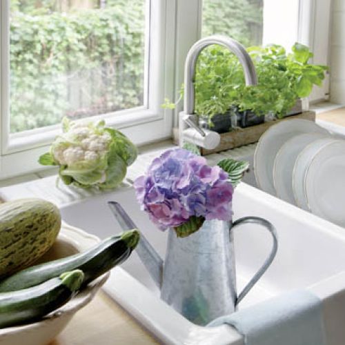 Świeże zioła w doniczkach na parapecie i warzywa i kwaty hortensji - ulubienicy pani domu.