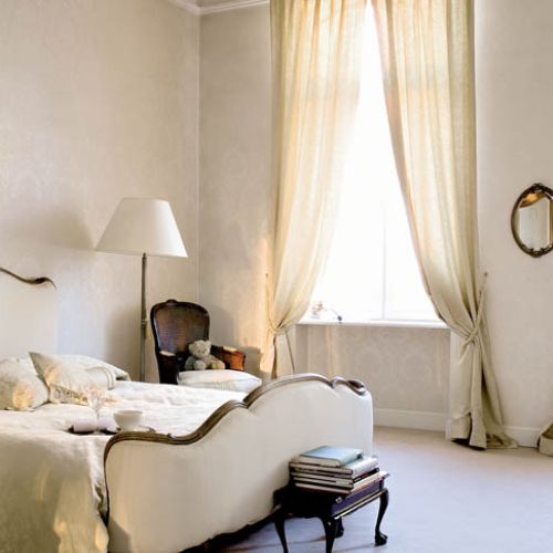 Sypialnia pani i pana domu urządzona jest w ciepłych odcieniach ecru.