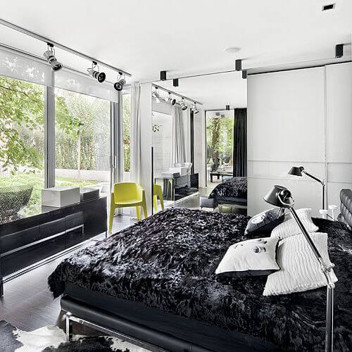 Sypialnia z panoramicznym oknem i dizajnerskimi smaczkami: stojace lampy Tolomeo (marki Artemide), czy poduszki z