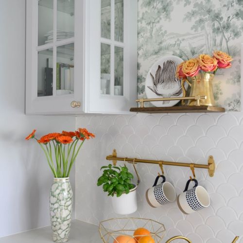 szara kuchnia z białym blatem i zieloną tapetą