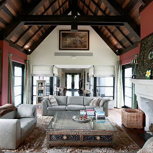 Szare kanapy i kominek z białego marmuru sprawiają, że orientalne dodatki nie przytłaczają wnętrza.