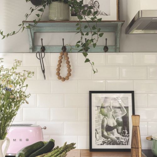 biała kuchnia z drewnianym blatem i zielonymi akcentami