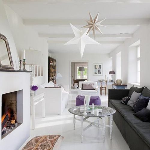 Tina kocha antyki i rękodzieło. Do białych ścian i podłóg odważnie dodaje ciemne poduchy, stare meble i chodniki.