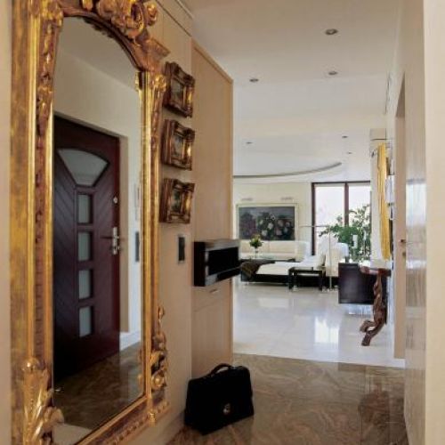 W holu wisi lustro w zdobionej złotej ramie.