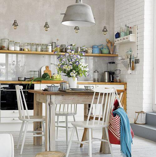 W jadalni drewniany okrągły stół i białe krzesła.