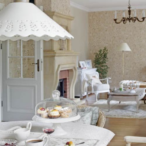 W jadalni meble ze starzonego bielonego dębu. Prosty ciężki stół, a przy nim rattanowe ogrodowe