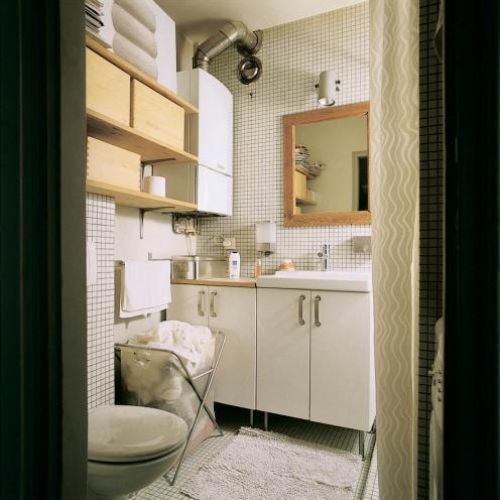 W jasnej łazience uwagę zwracają drewniane akcenty.