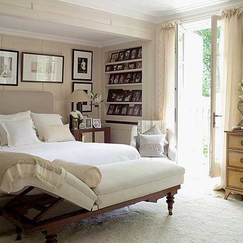 W jasnej sypialni równe rzędy ramek wprowadzają wrażenie porządku.