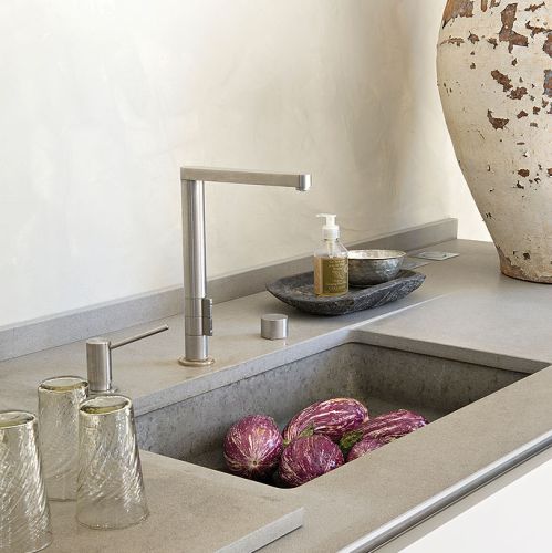 W kuchni stare przeplata się z nowym: nowoczesne, dizajnerskie baterie przy zlewozmywaku.