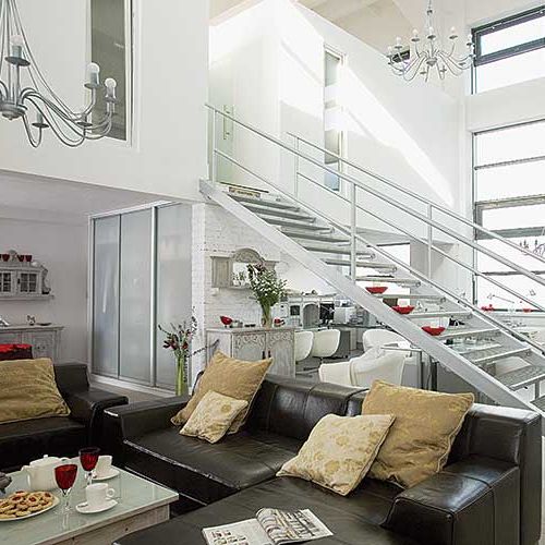 W salonie ciemne skórzane kanapy rozjaśniają poduszki.