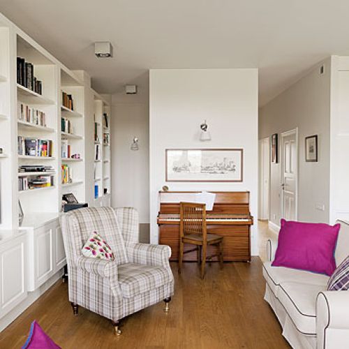 W salonie stoi duża stylizowana biblioteka, całości dopełniają dizajnerskie lampy Artemide.