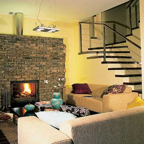 W salonie uwahę zwraca ceglana ściana-obudowa kominka.