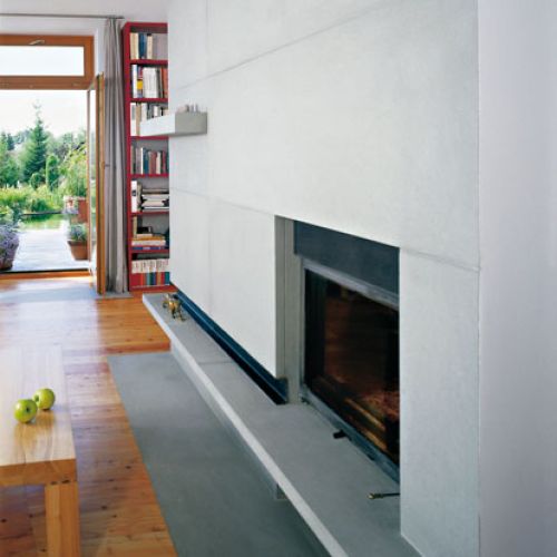 We wnętrzu, podobnie jak na elewacji, postawiono na kamień i drewno. Minimalistyczny kominek obudowano kamieniem.