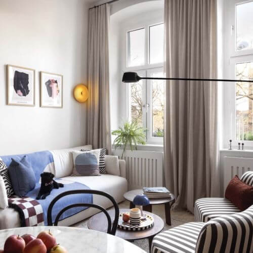 sofa i fotel w pasy w eklektycznym salonie w kamienicy
