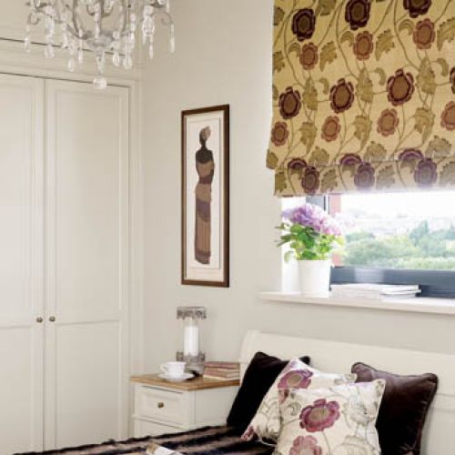 Zdecydowany kwiatowy wzór na tkaninach i kolor bakłażana świetnie uzupełniają delikatne meble w kolorze ecru.