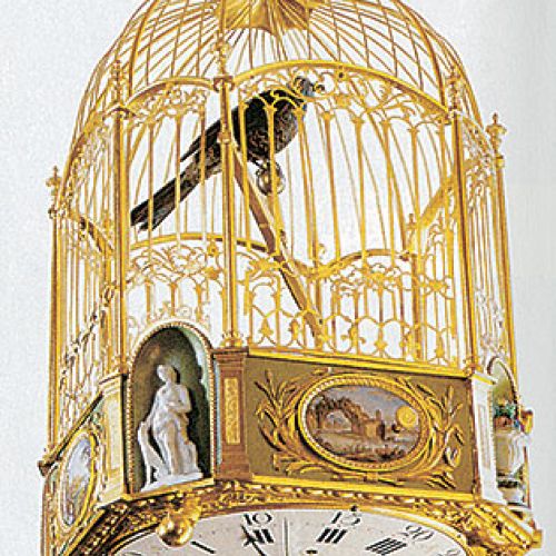 Złocona klatka z ptakiem zdobiona porcelanowymi figurkami i malowidłami, na spodzie tarcza zegarowa, II poł.