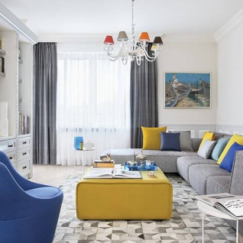 Żółty puf, białe stoliki, poduchy i dywan z kawałków skóry przyjechały z BoConcept. Na ścianach obrazy Dariusza Żejmy z