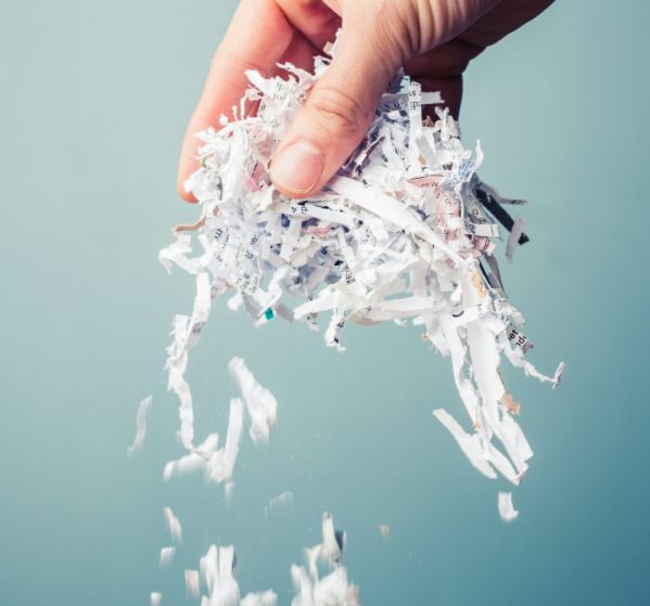 kobieta wkłada kartki papieru do niszczarki dokumentów