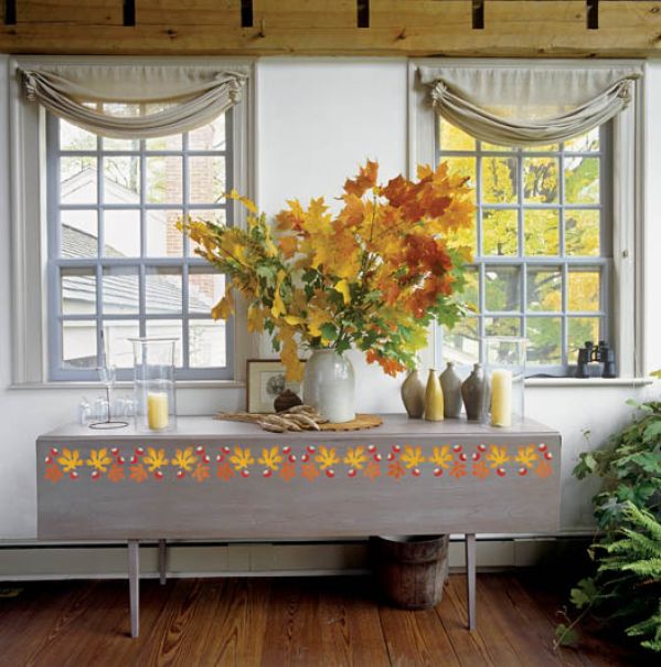 Wielki bukiet jesiennych liści i jesienny wzor wymalowany na stole.