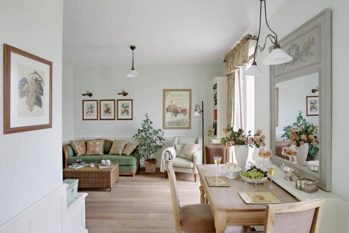 Na zielonej kanapie leżą poduszki obszyte tkaniną w róże.