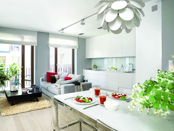 Szafki kuchenne zrobione na zamówienie z lakierowanego MDF-u. Sofa marki Dublo, dywan, szare poduchy i koc - Belbazaar.