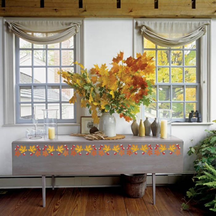 Wielki bukiet jesiennych liści i jesienny wzor wymalowany na stole.