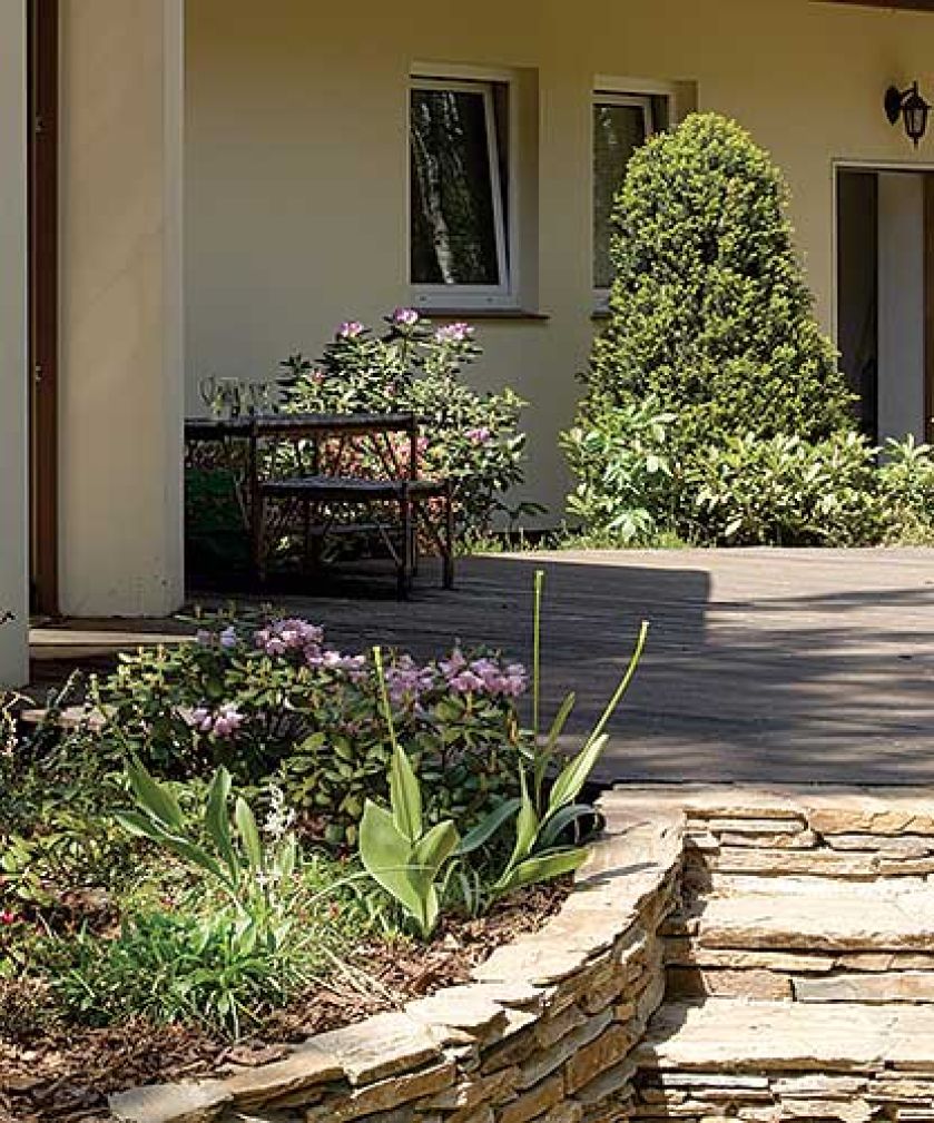 W okół domu otoczone kamieniem rabaty.