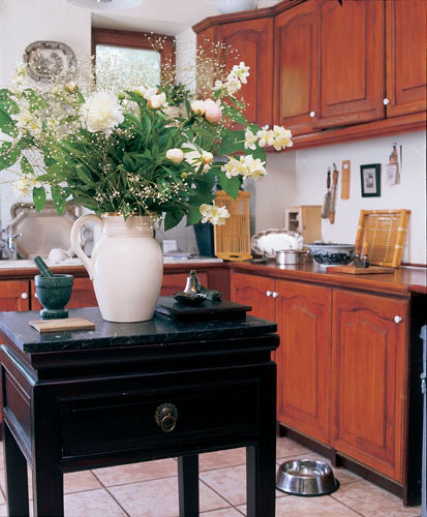 Czarny stolik z drewnianym blatem na środku kuchni sprawia, że z jadalni nie widzimy kuchennego rozgardiaszu.