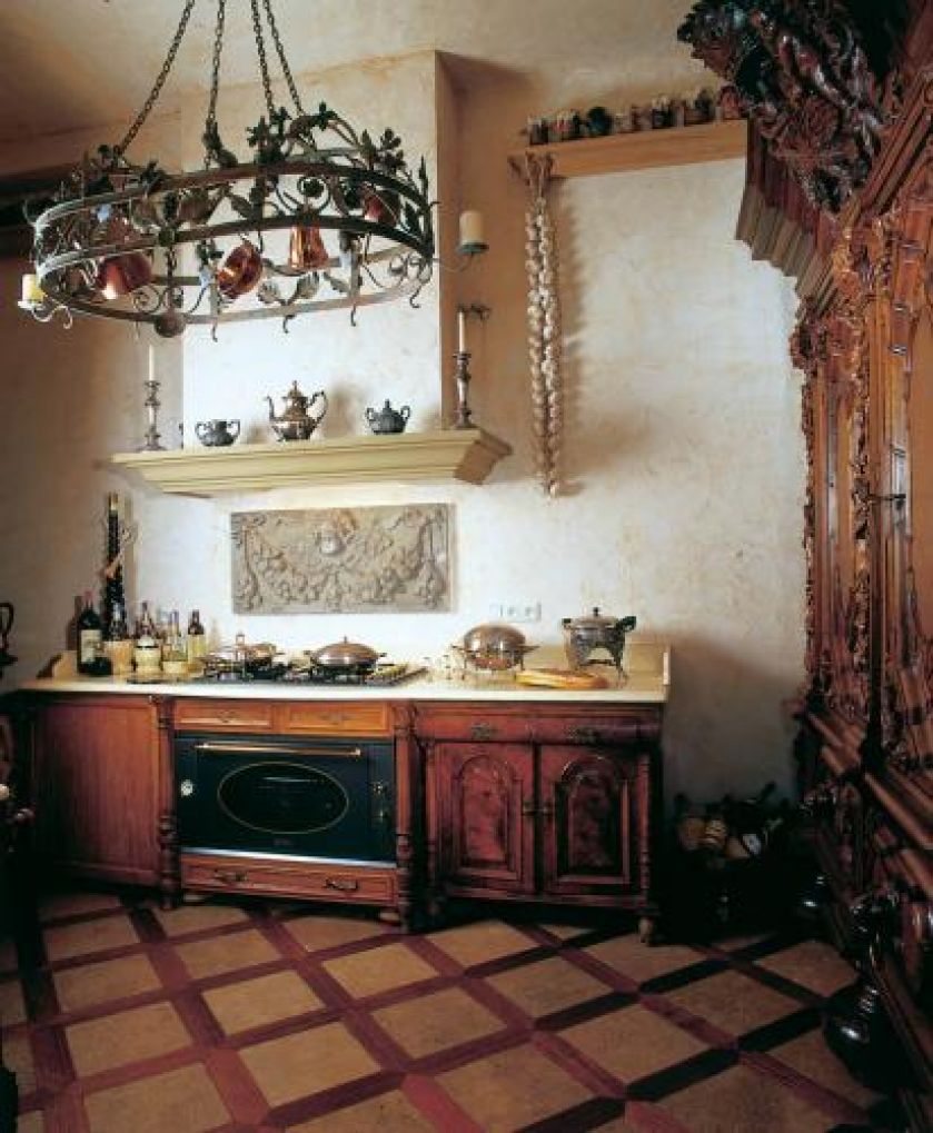 Stylizowane na stare komody szafki kuchenne przykryto kamiennym blatem. Gzyms komina jest z piaskowca.