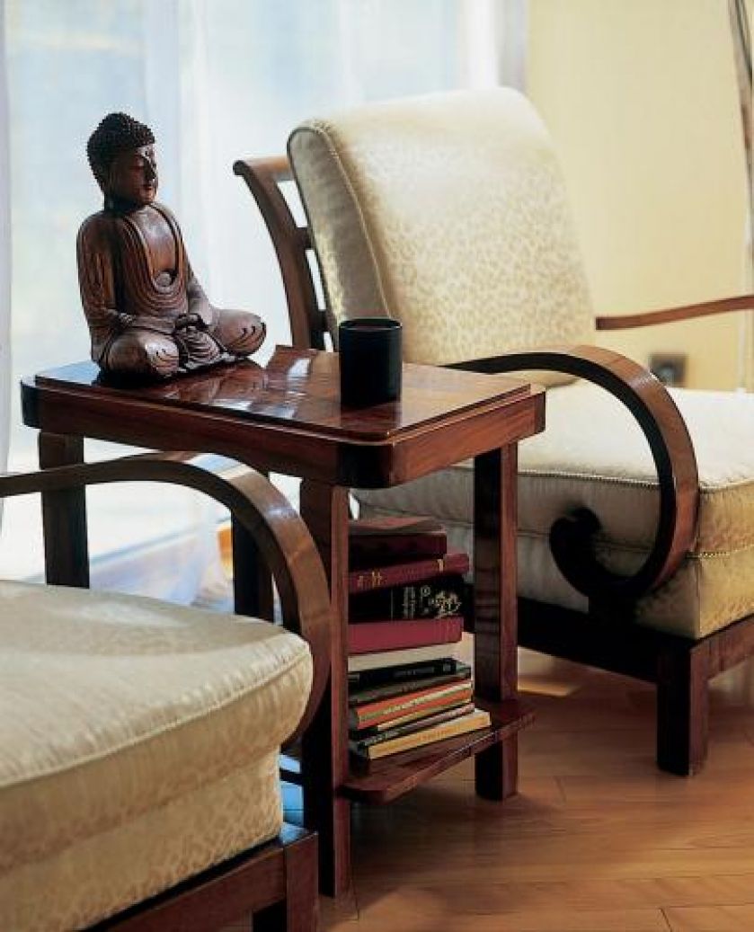 Drewniany posążek stoi na stoliku między dwoma fotelami.