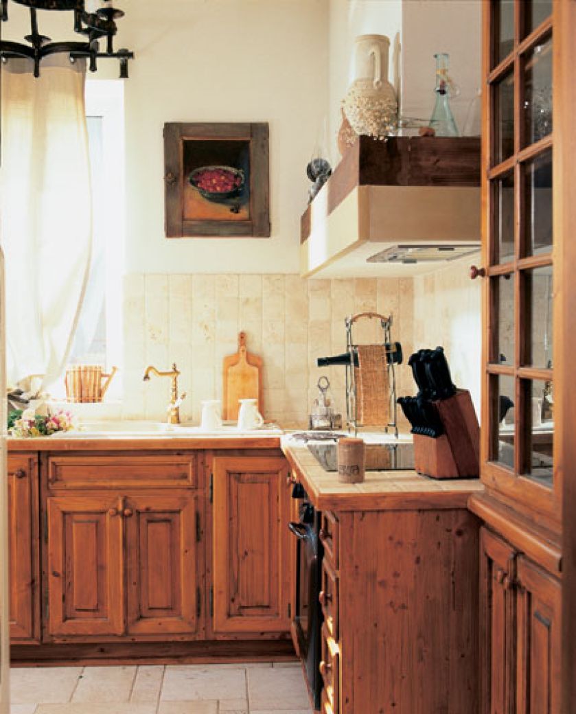 Francuski sznyt dodają kuchni trawertynowe płytki ? na ścianie i blacie małe, na podłodze w różnych formatach.