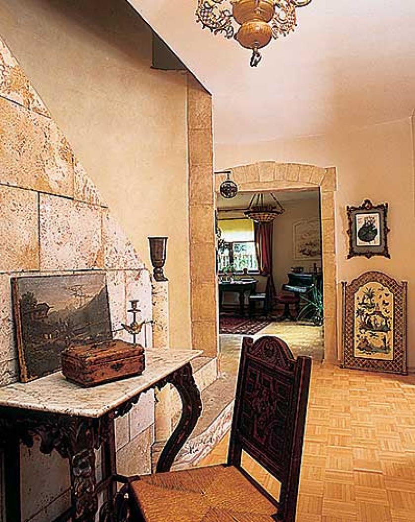 Pod kamienną ścianą stoi zdobiona konsola.