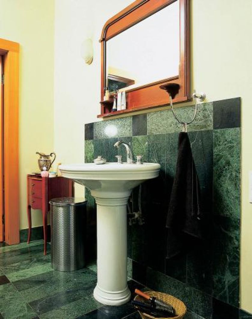 Nad umywalką wisi lustro w drewnianej ramie.