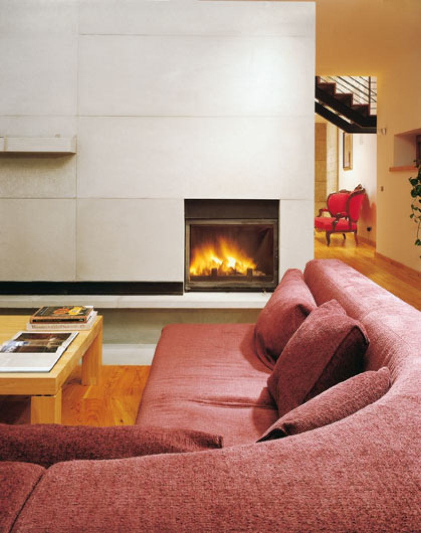 Przed minimalistycznym kominkiem mozna się rozsiąść w na wygodnej kanapie.