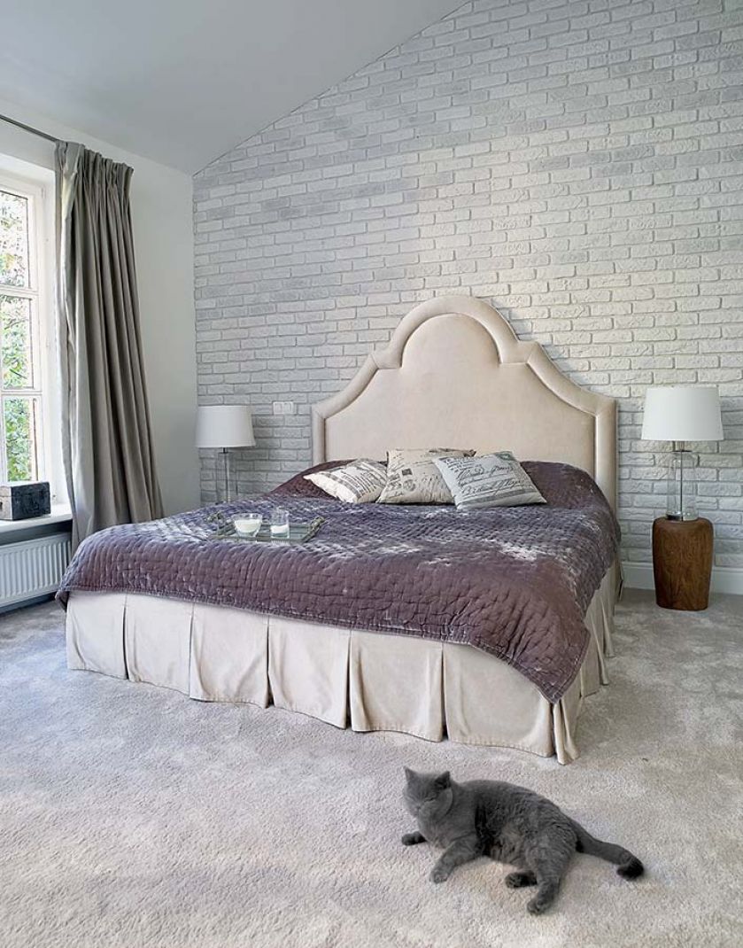 Stylowy mix: pałacowe łóżko, ceglana ściana jak w lofcie i rustykalne stoliki pieńki (z Belbazaar).