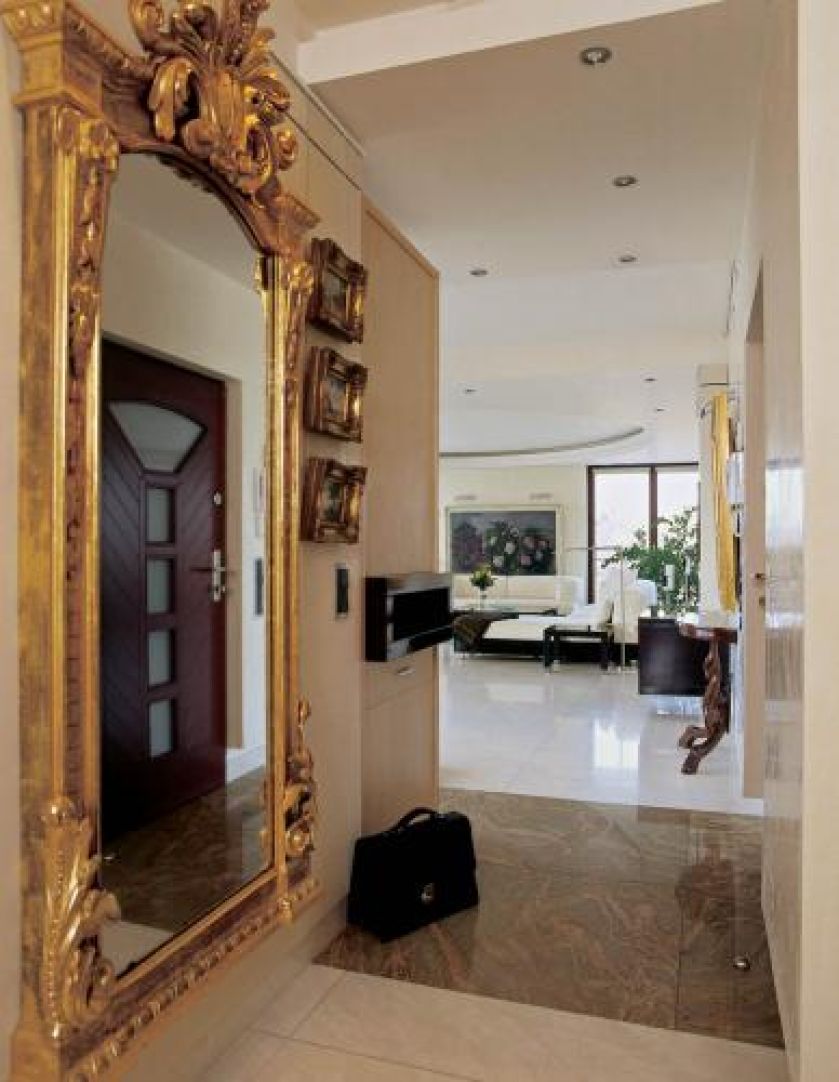 W holu wisi lustro w zdobionej złotej ramie.