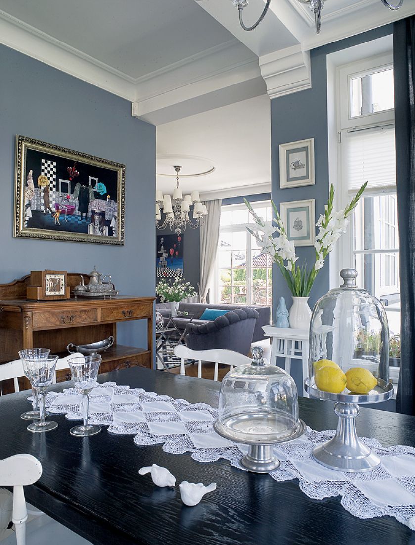 Na ścianie sztuka współczesna, na stole koronkowy bieżnik w stylu vintage.