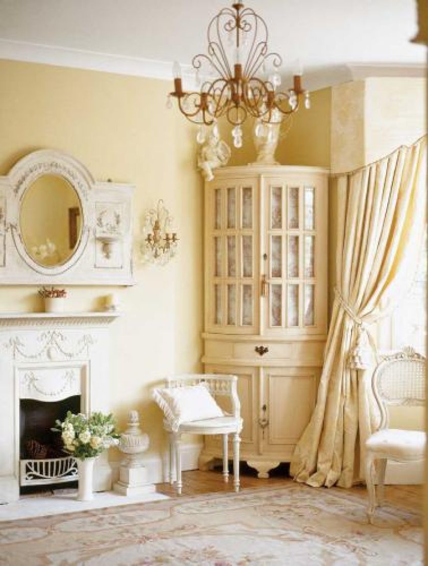 Narożna szafa, kominek i kryształowy żyrandol.