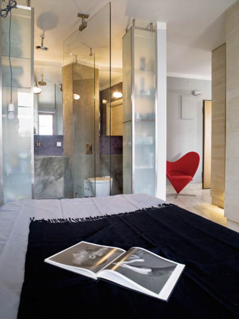 W łazience beton na ścianach i wielka tafla szkła (jednocześnie obrotowe drzwi) oddzielająca prysznic od sypialni. Odważnie i ciekawie.