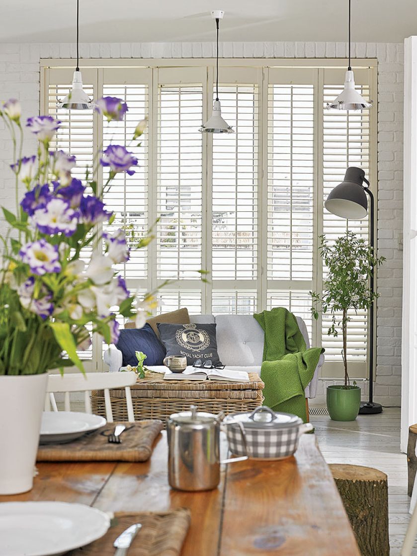 Dominującą biel przełamują delikatne zielenie oraz kolory dekoracji - także sezonowych kwiatów w wazonie.