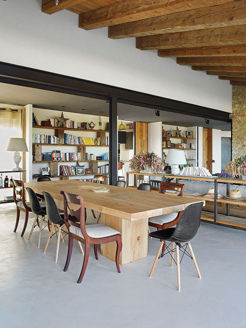 Eklektyczna jadalnia: betonowa podłoga, drewniany stół, artdecowskie i nowoczesne krzesła.