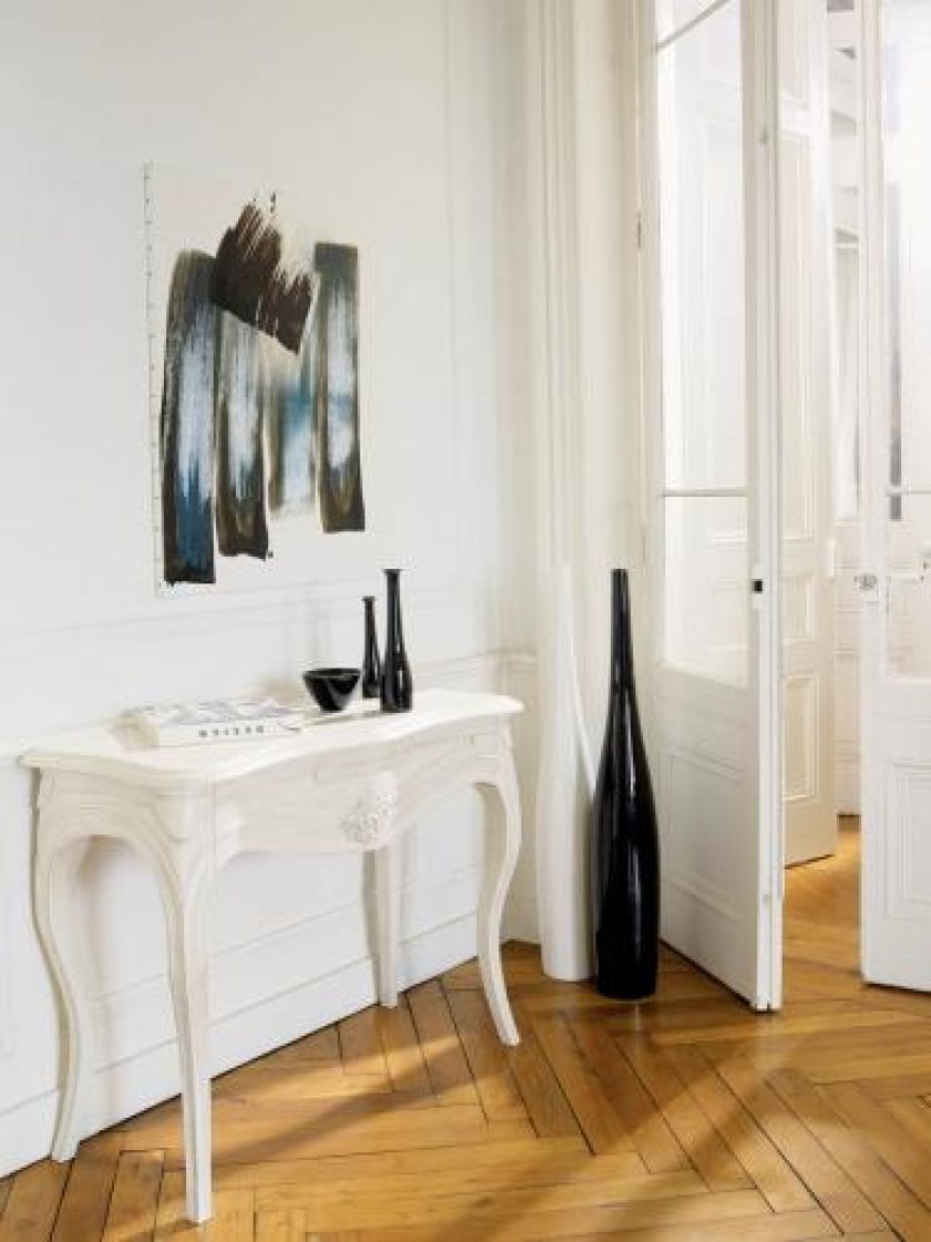 Jak na szachownicy. Biel ściany, stolika i drzwi złamano czarnymi dodatkami i drewnianym parkietem. GRANGE