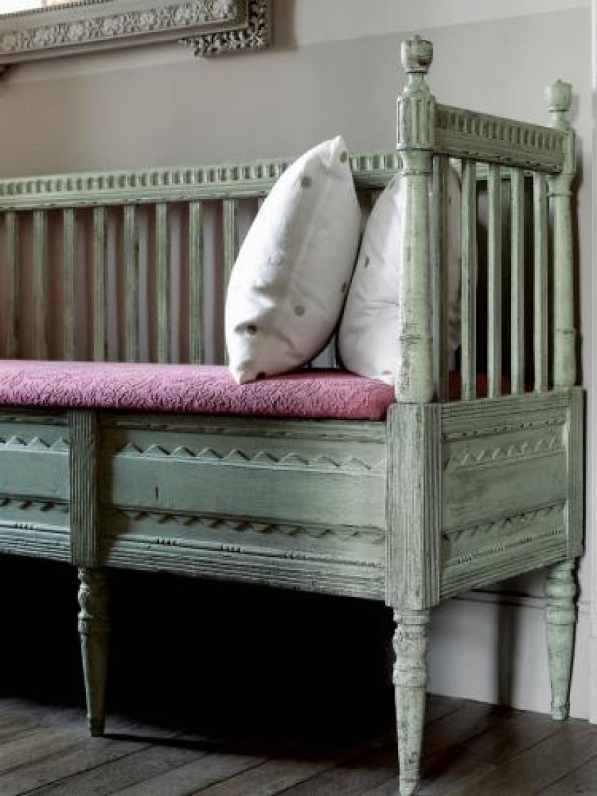 Na drewnianej ławie leżą poduszki w grochy.