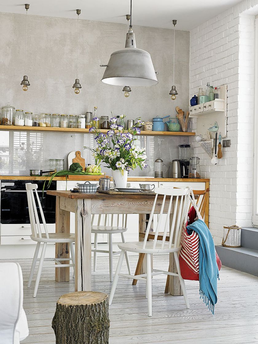 W jadalni drewniany okrągły stół i białe krzesła.