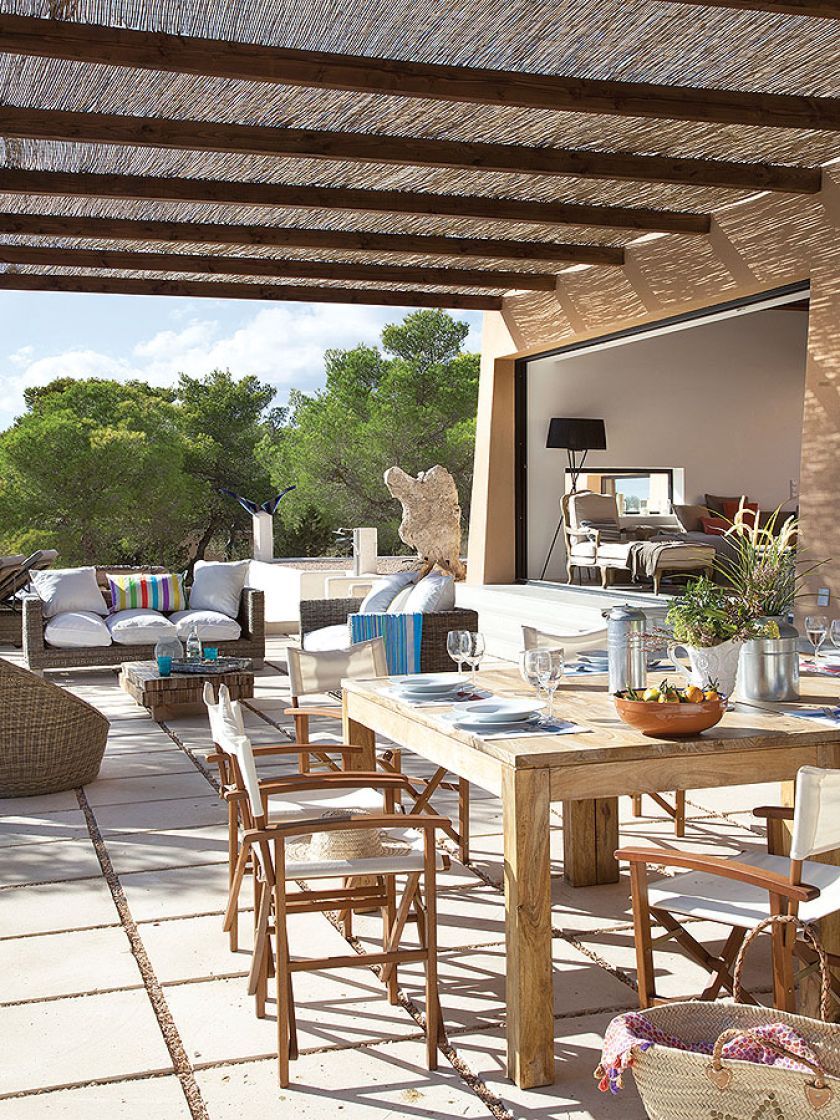 Taras z jadalnią: drewniany stół, krzesła, a obok wygodne kanapy.